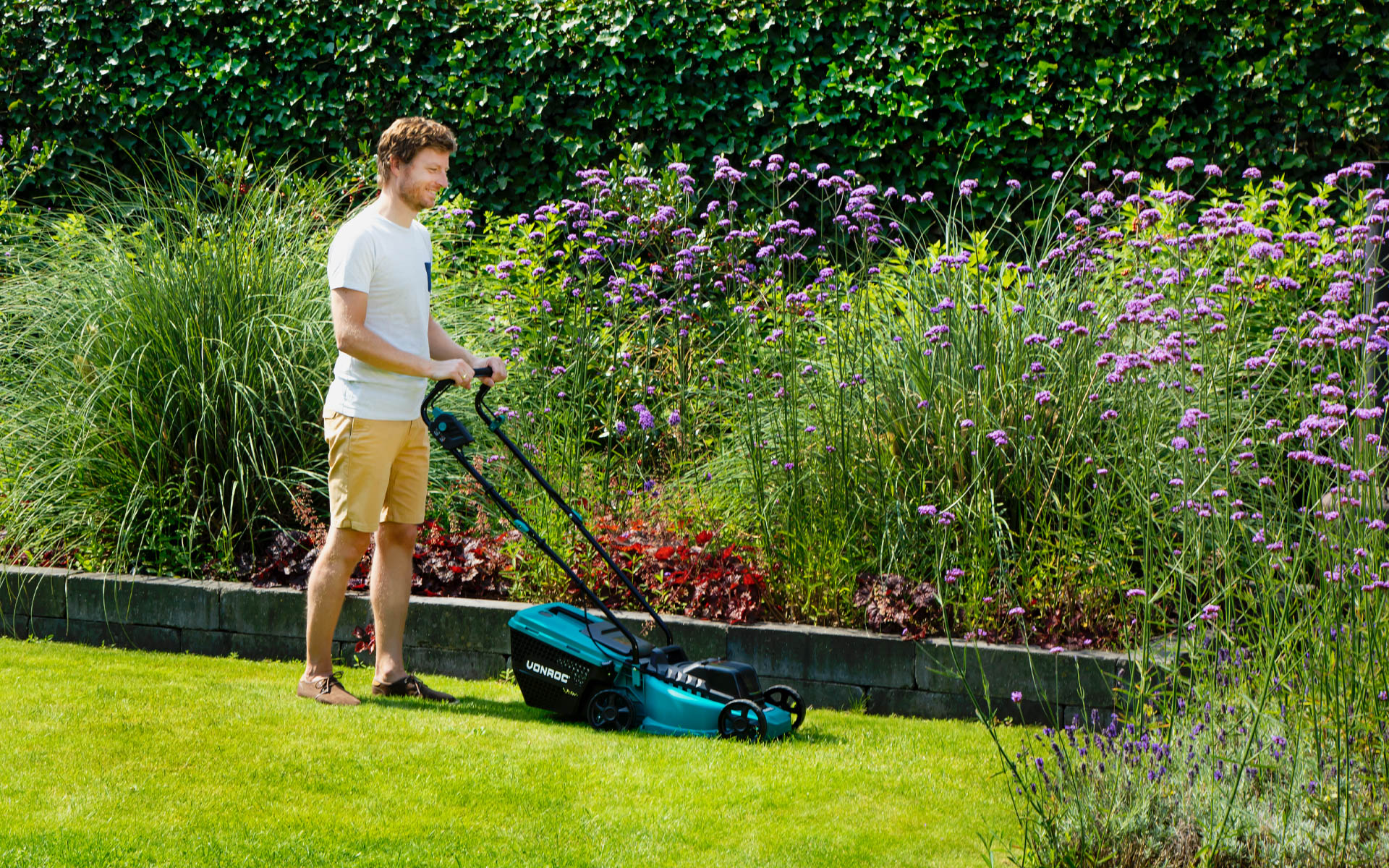 Mand, der slår græs med en VONROC plæneklipper
